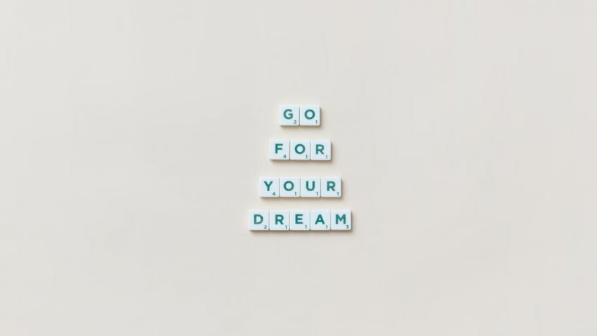 Inspirational text 'Go For Your Dream' made from Scrabble tiles on a plain background.